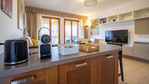 A modern kitchen with a central island, a toaster, a kettle, and a flat-screen TV. - Wrap around Lake Views Family sized condo with large balcony (Campione d'Italia)