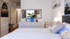 A bedroom with a bed, dresser, mirror, potted plants, and artwork on the walls. - Wrap around Lake Views Family sized condo with large balcony (Campione d'Italia)