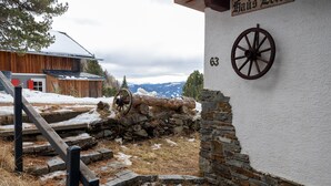 Un edificio rústico con un muro de piedra y una escalera de madera que lleva a una puerta.