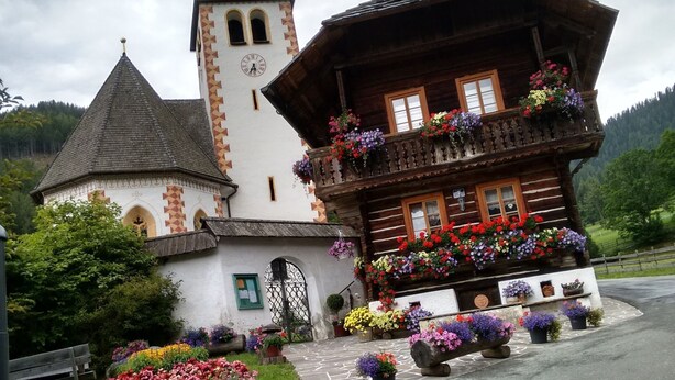 A traditional wooden building with a bell tower and a balcony adorned with colorful flowers. - Holiday Home in Bad Kleinkirchheim (Bad Kleinkirchheim)