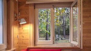 A wooden cabin room with a large window, a red bench, and a wall-mounted lamp. - Gierle Garden Bungalow Escape (Lille)