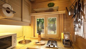A compact kitchen with a microwave, sink, stove, and various utensils. - Gierle Garden Bungalow Escape (Lille)