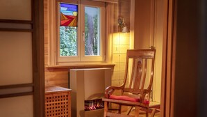 A cozy room with a wooden rocking chair, a fireplace, and a window with stained glass. - Gierle Garden Bungalow Escape (Lille)