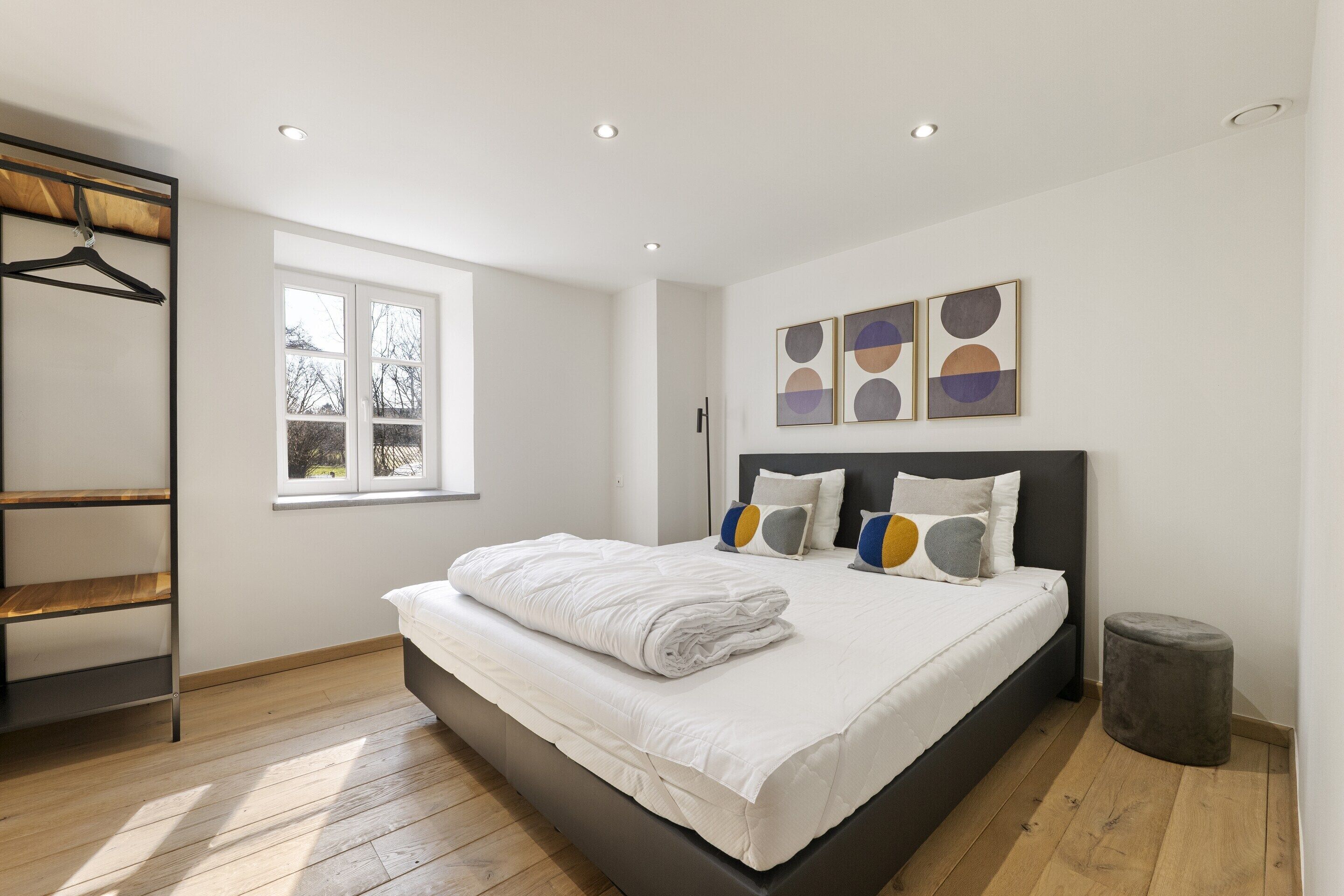 Une chambre moderne avec un grand lit, une fenêtre et une étagère fixée au mur.