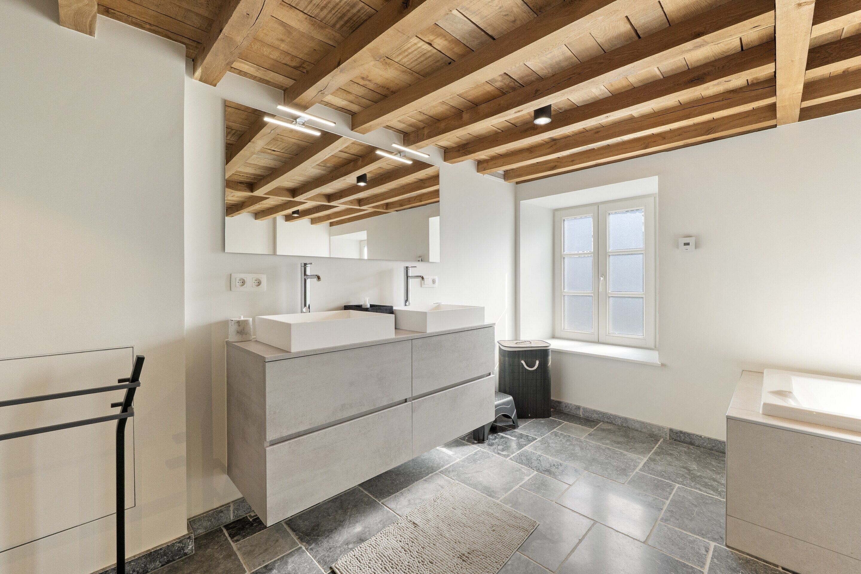 Une salle de bain moderne avec un grand meuble-lavabo, un miroir et une fenêtre.