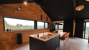 Una cocina moderna con una isla grande, paredes de madera y ventanas amplias que ofrecen vistas al exterior.