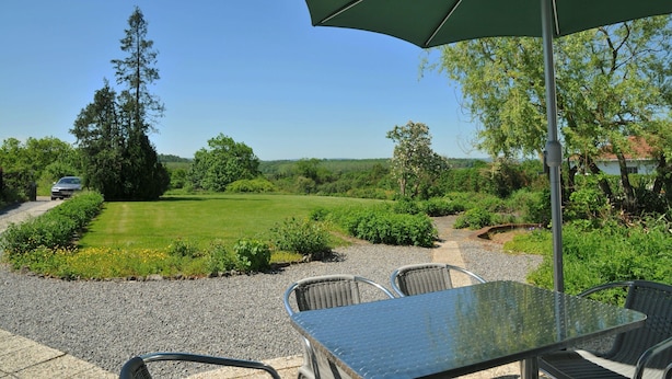 Eine Terrasse mit Tisch und Stühlen, umgeben von einem Kiesweg und Grünpflanzen.