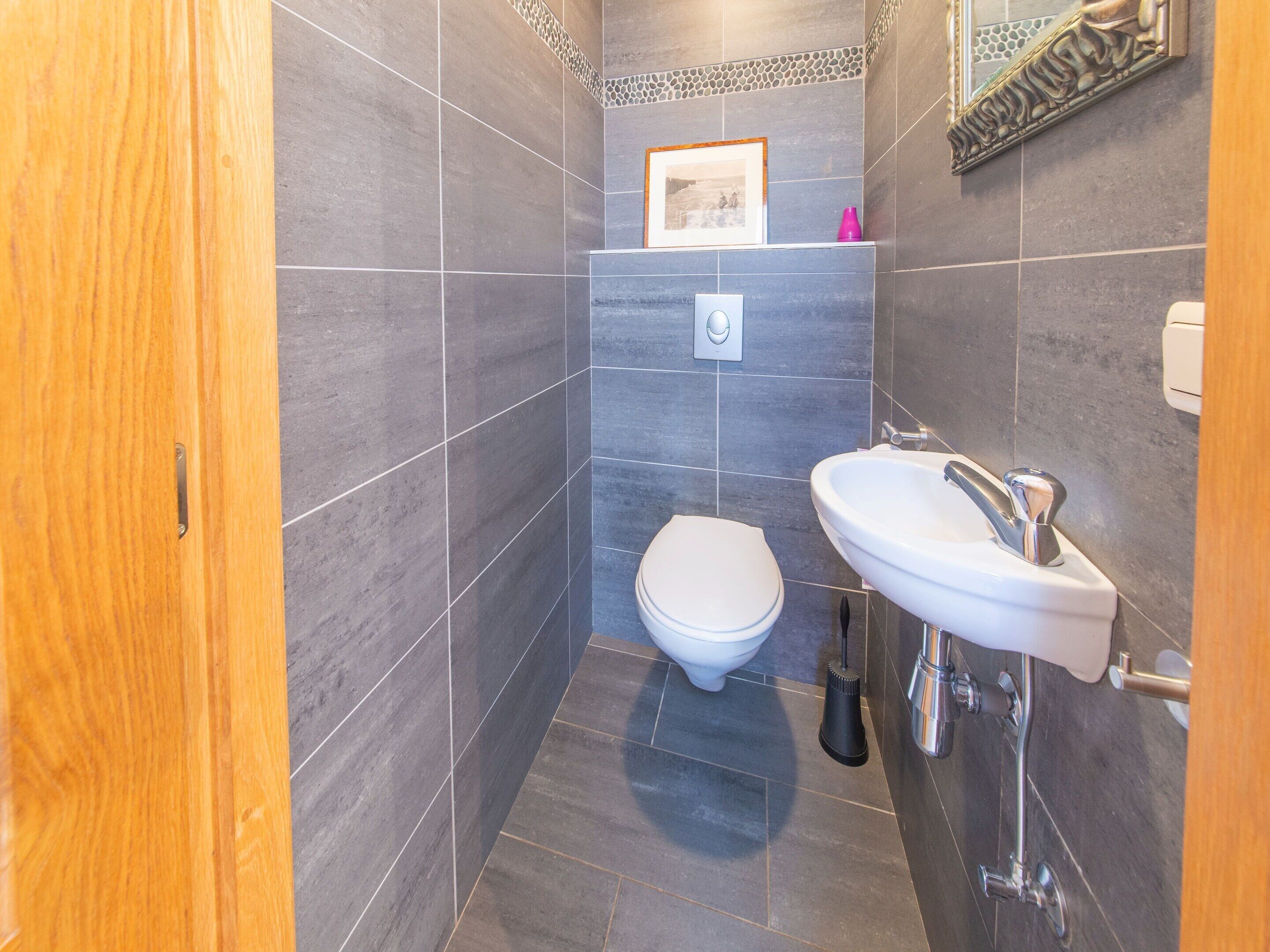 A modern bathroom with a toilet, sink, and shower.