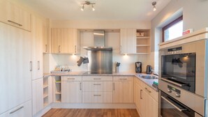A modern kitchen with light wood cabinets, stainless steel appliances, and a wooden floor. - Holiday Home in Borlon With Terrace (Durbuy)