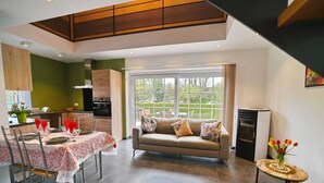 A modern living room with a sofa, dining table set for four, and a kitchen in the background.