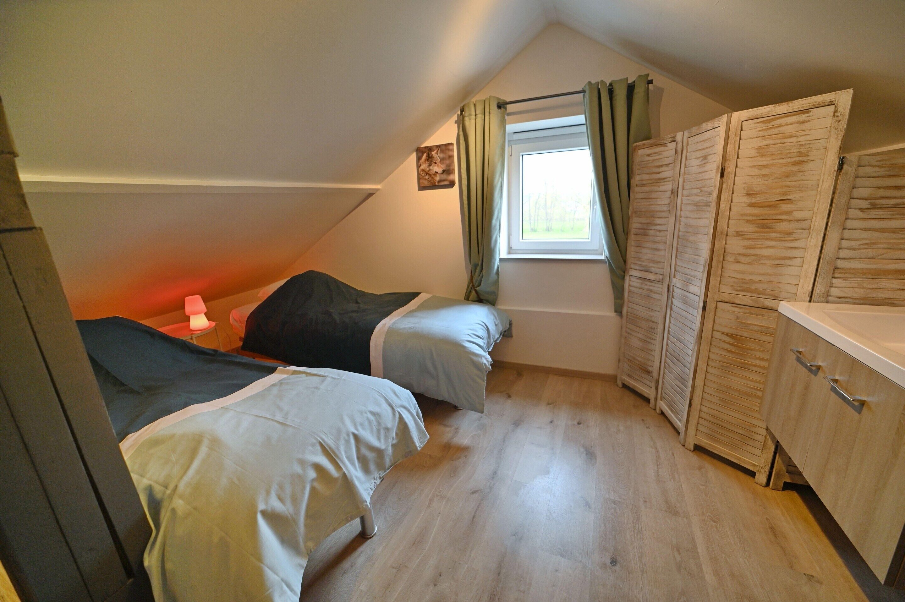 Un dormitorio pequeño y acogedor con dos camas, una ventana con cortinas y armarios de madera.
