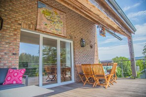 A covered patio with wooden furniture, a map on the wall, and a glass door leading to an outdoor area. - Holiday Home With a Terrace in Warisy (Rendeux)