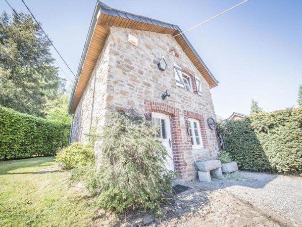 A stone building with a sloped roof, a small porch, and a gravel driveway. - Holiday Home Le Fournil in Manhay With Garden (Manhay)