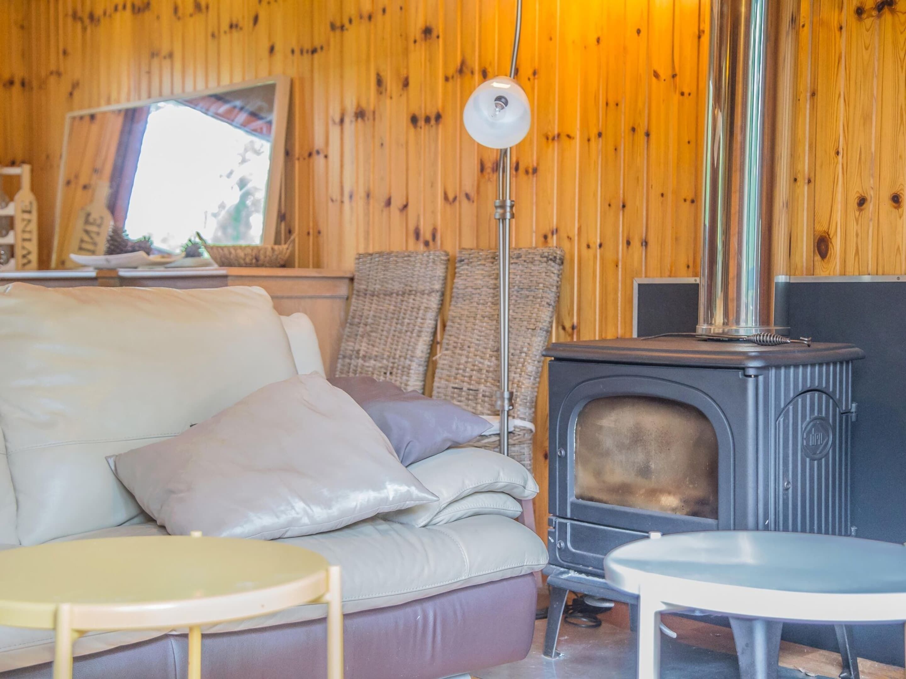 A cozy room with a sofa, two chairs, a small table, and a wood-burning stove.