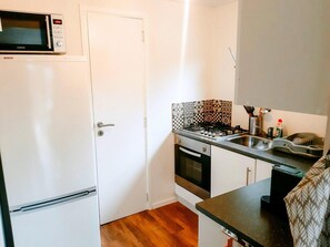 Kompakti keittiö, jossa on mikroaaltouuni, liesi, uuni ja pesuallas.