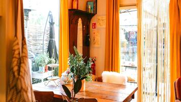 Een houten eettafel met stoelen, een potplant en een klein tafeltje met een kaars.