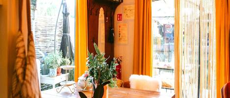 A wooden dining table with chairs, a potted plant, and a small table with a candle.