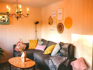A cozy living room with a sofa, cushions, a table with a vase, a chandelier, and wall decorations. - Beautiful Romantic Chalet in Geel (Geel)
