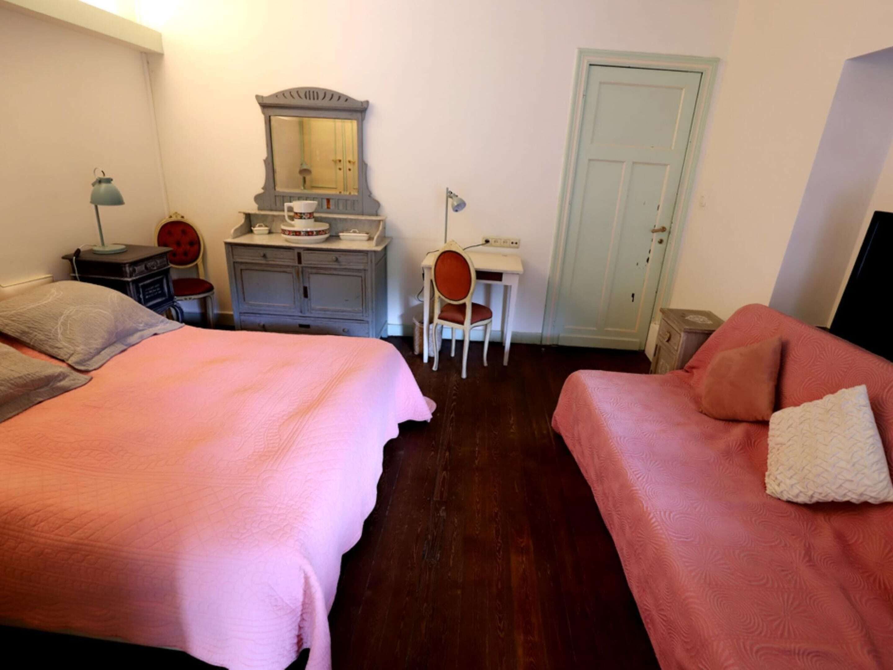 Une chambre avec deux lits, un bureau, une chaise, une commode et une porte.