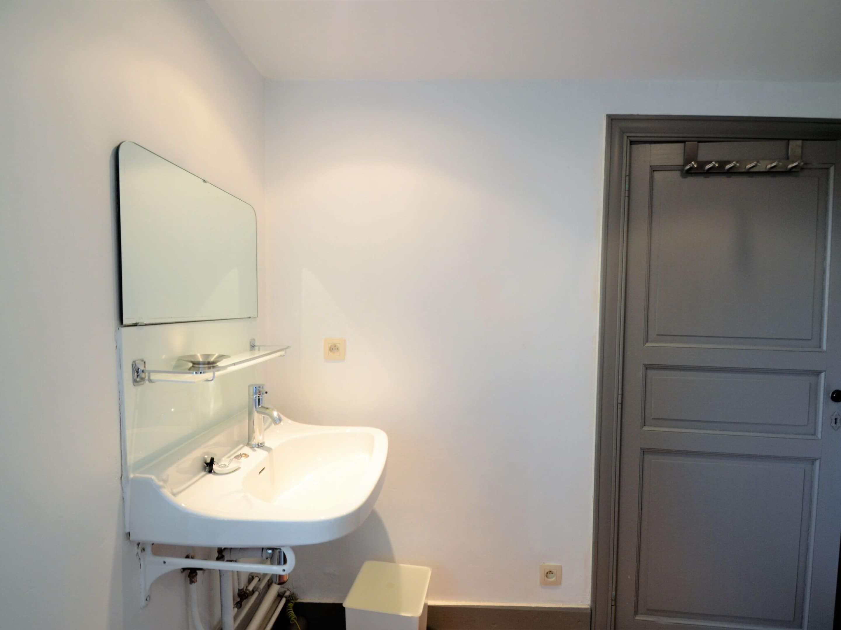 A bathroom with a white sink, a mirror, and a door.