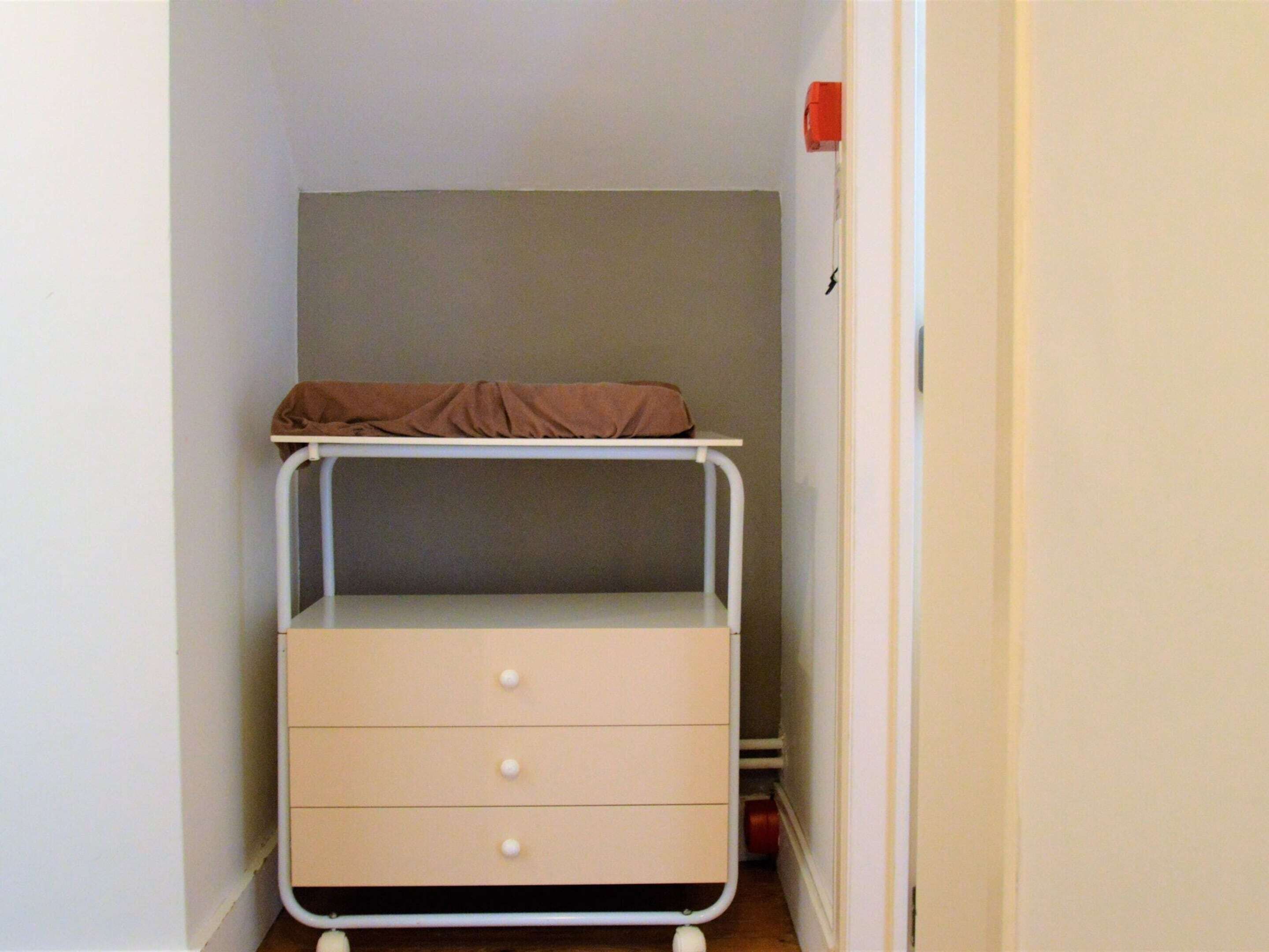 A small, narrow room with a bunk bed and a single drawer unit.