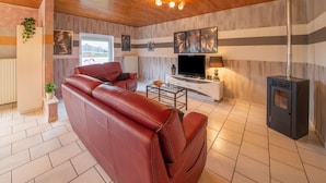 A modern living room with a leather sofa, a TV, a fireplace, and a wooden ceiling. - Sweet Home in Chiny With Garden (Chiny)