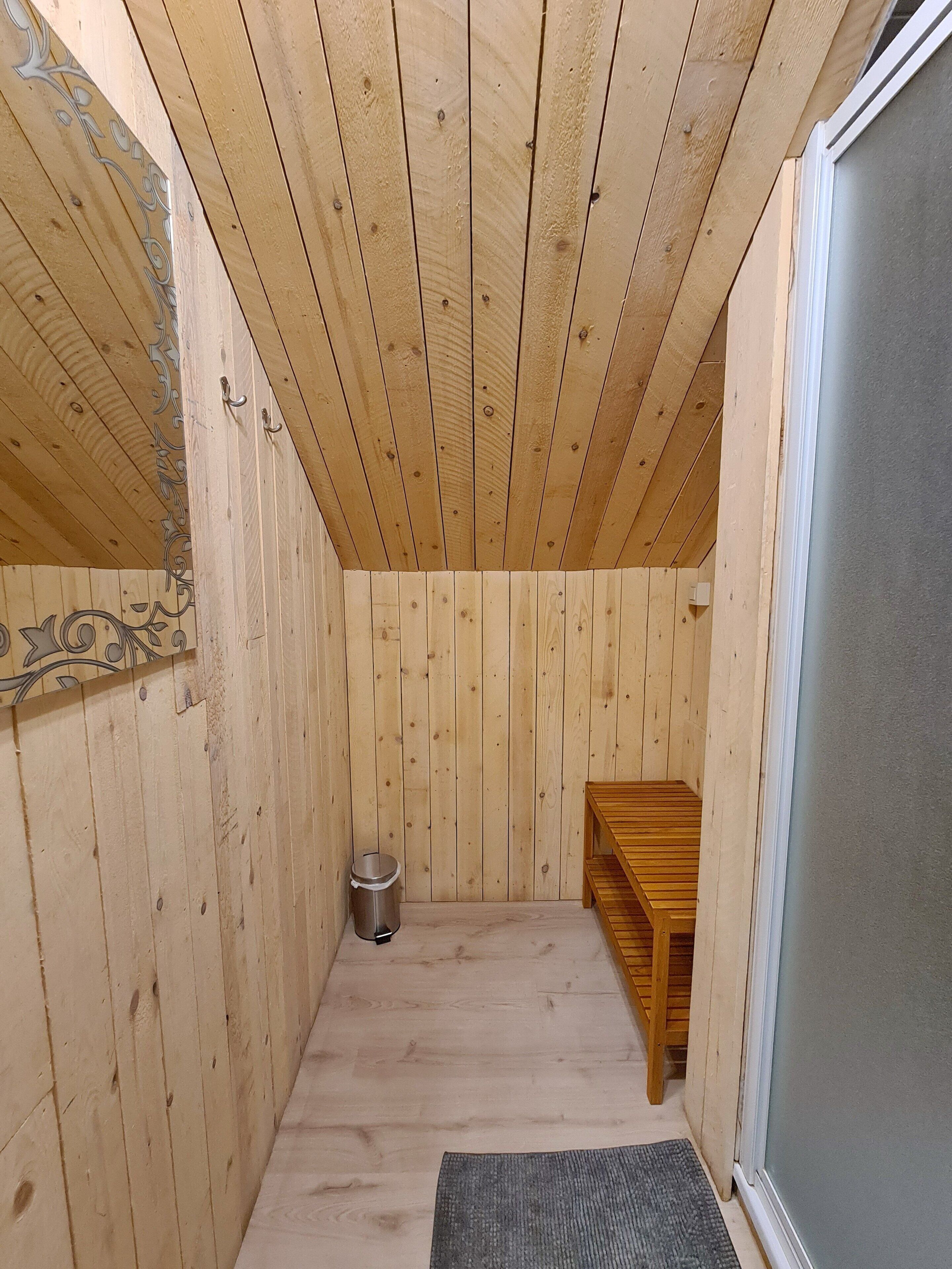 Ett rum med träpanel, en bänk, en papperskorg och en dörr.