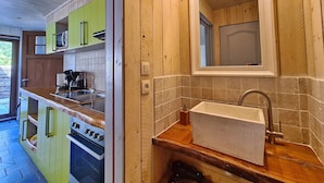 Ett kök med träskåp, en inbyggd ugn och en diskho med en spegel ovanför.