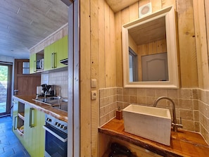 A kitchen with wooden cabinets, a built-in oven, and a sink with a mirror above it.