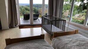 Een slaapkamer met twee bedden, een raam met uitzicht op de omgeving en een balkon met een stoel en een tafeltje.