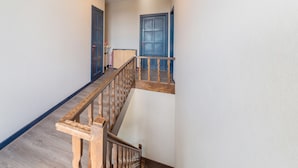 Una escalera con barandillas de madera y una plataforma con una puerta azul.
