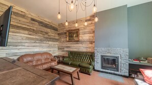 Una sala de estar con chimenea, sofás de cuero, una mesa de centro y un televisor montado en la pared.