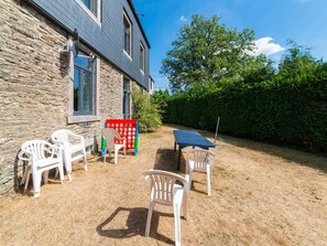 A stone building with a blue roof, a ping pong table, and several white plastic chairs. - Elegant Home in Bievre With Garden (Bievre)