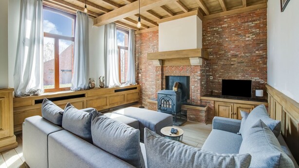 A living room with a brick fireplace, wooden beams, a sofa set, and a television. - Beautiful Holiday Home in Merksplas With Garden (Merksplas)
