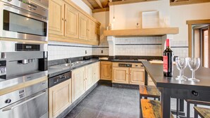 A modern kitchen with stainless steel appliances, wooden cabinets, and a stone tile floor. - Beautiful Holiday Home in Merksplas With Garden (Merksplas)