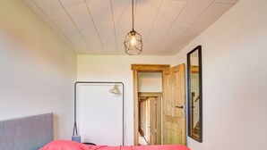 A bedroom with a bed, a hanging light fixture, a door, and a mirror on the wall. - Beautiful Holiday Home in Merksplas With Garden (Merksplas)