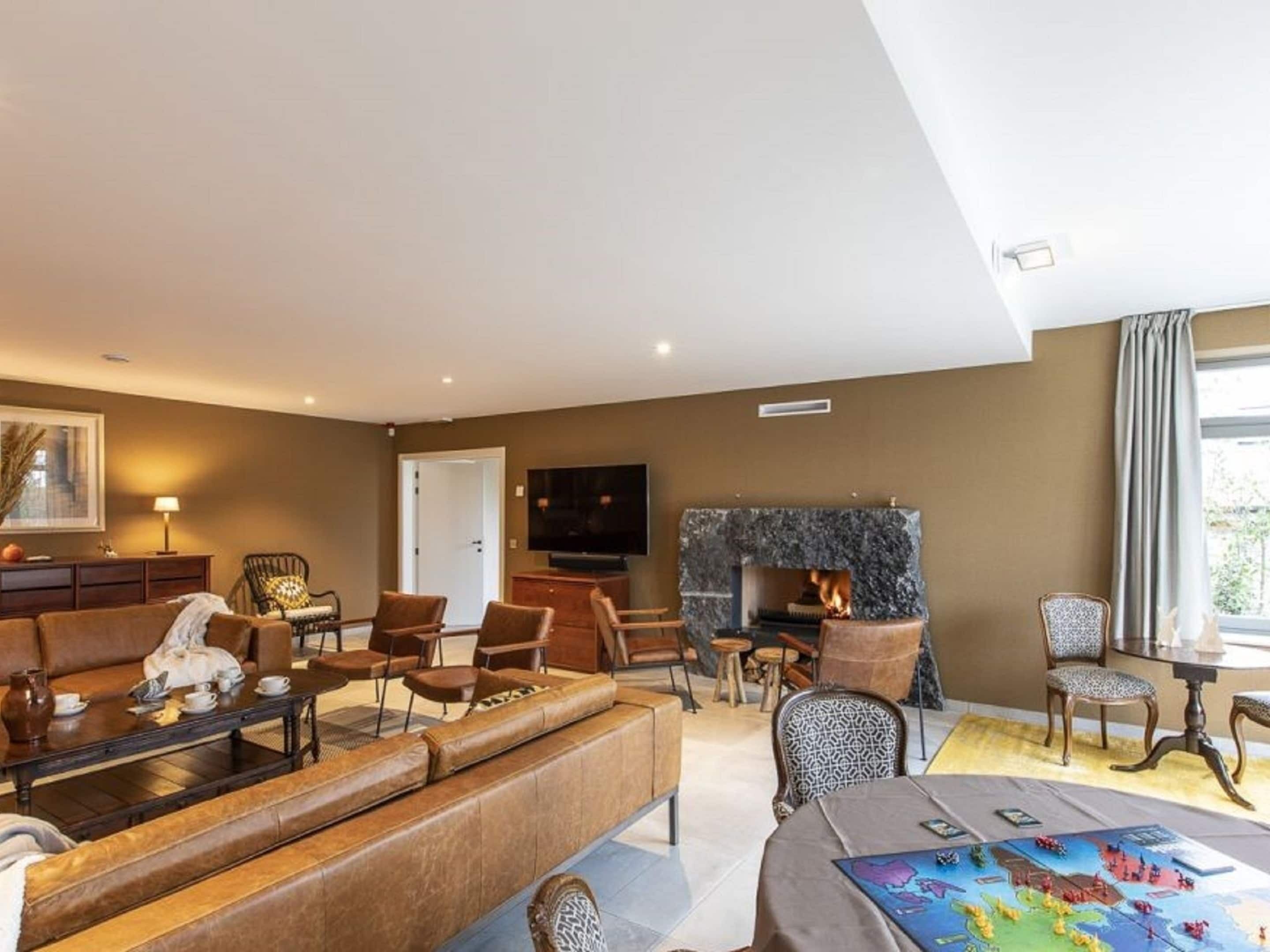 A spacious living room with a large sofa, a fireplace, and a dining area with a table and chairs.