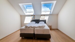 A bedroom with a skylight, a bed, and a small stool. - Charming Rural Retreat (Gedinne)