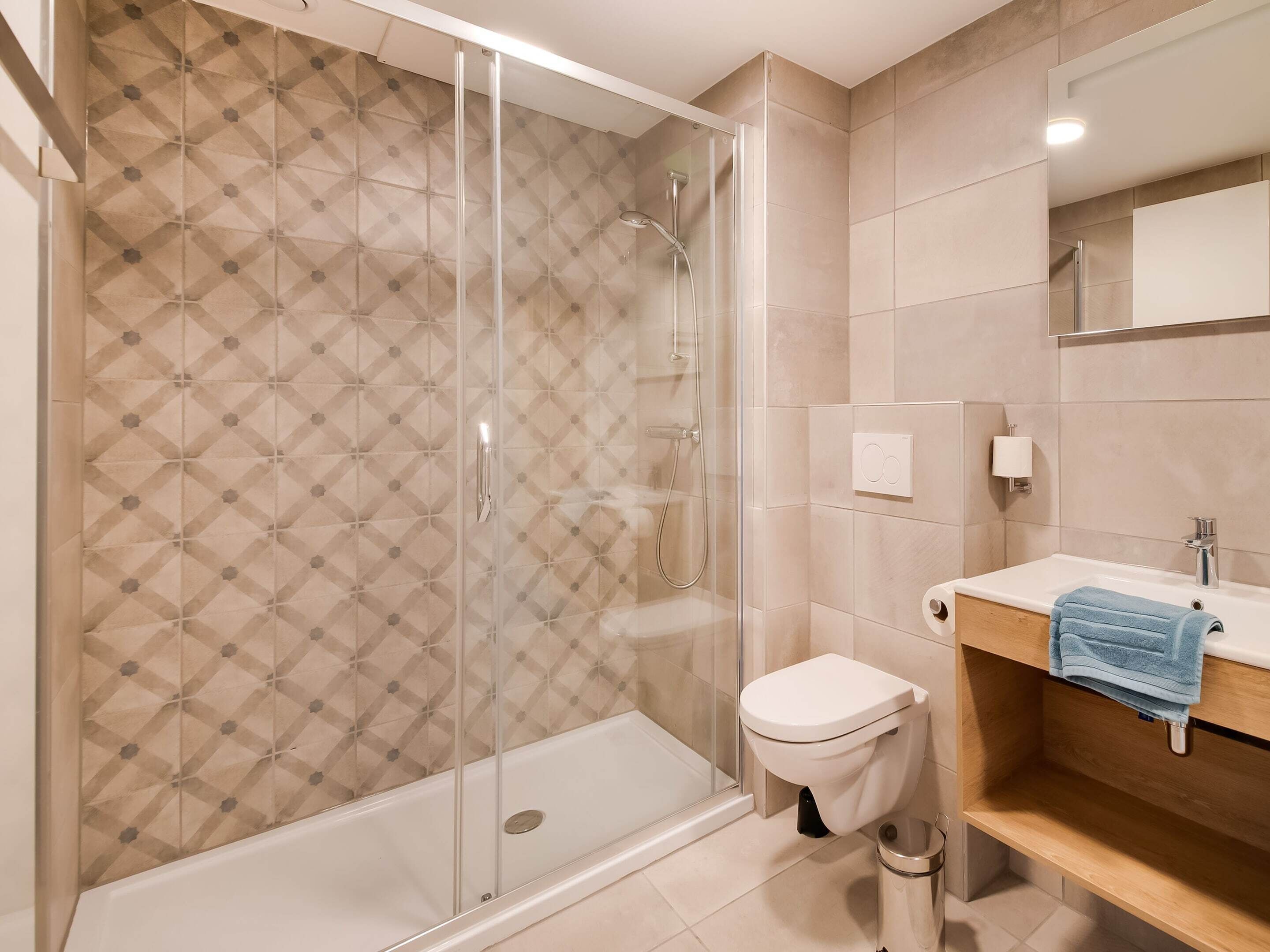 Une salle de bain moderne avec une douche, des toilettes et un lavabo, avec une serviette suspendue sur le côté.