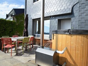 Un patio al aire libre con mesa y sillas, una terraza de madera y un jacuzzi.