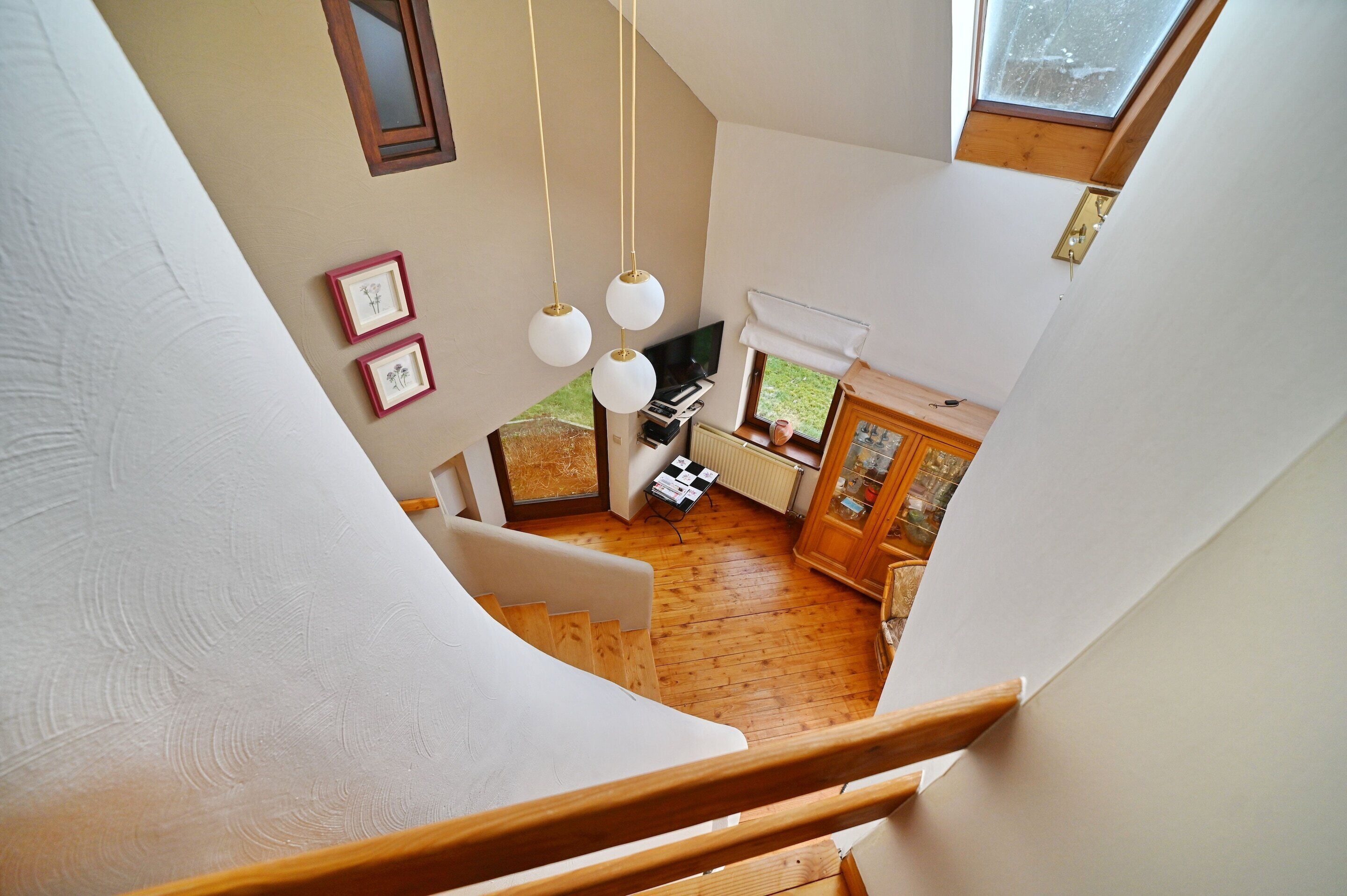 Una habitación con techos altos, una escalera de madera, un pequeño rincón de cocina y vistas al exterior.