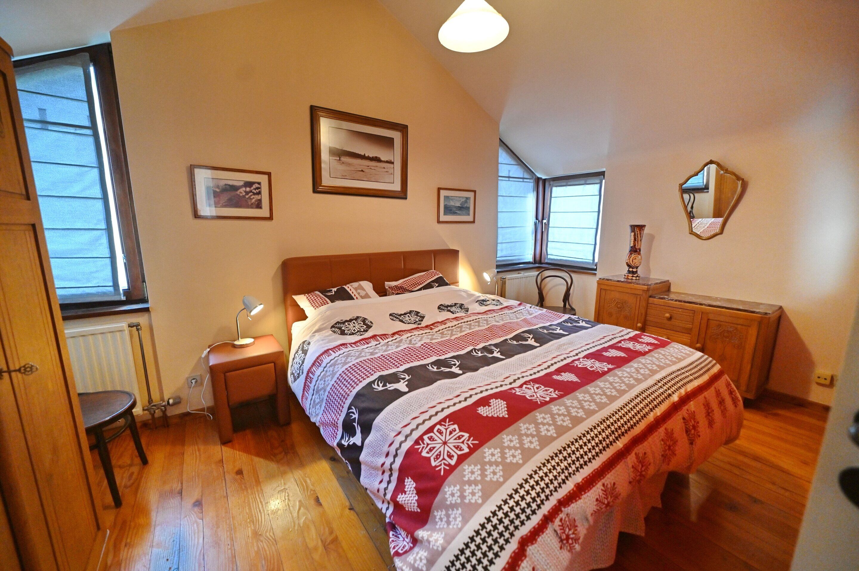 Un dormitorio con una cama grande, una mesita de noche, una silla, un aparador y una ventana.
