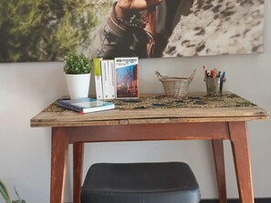 A wooden table with a woven placemat, a potted plant, a basket, and a collection of books and pens. - Beautiful Holiday Home in Alken With a Garden (Alken)