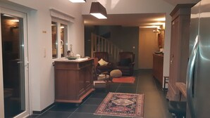 Un couloir avec une armoire en bois, une chaise, un tapis et un réfrigérateur.
