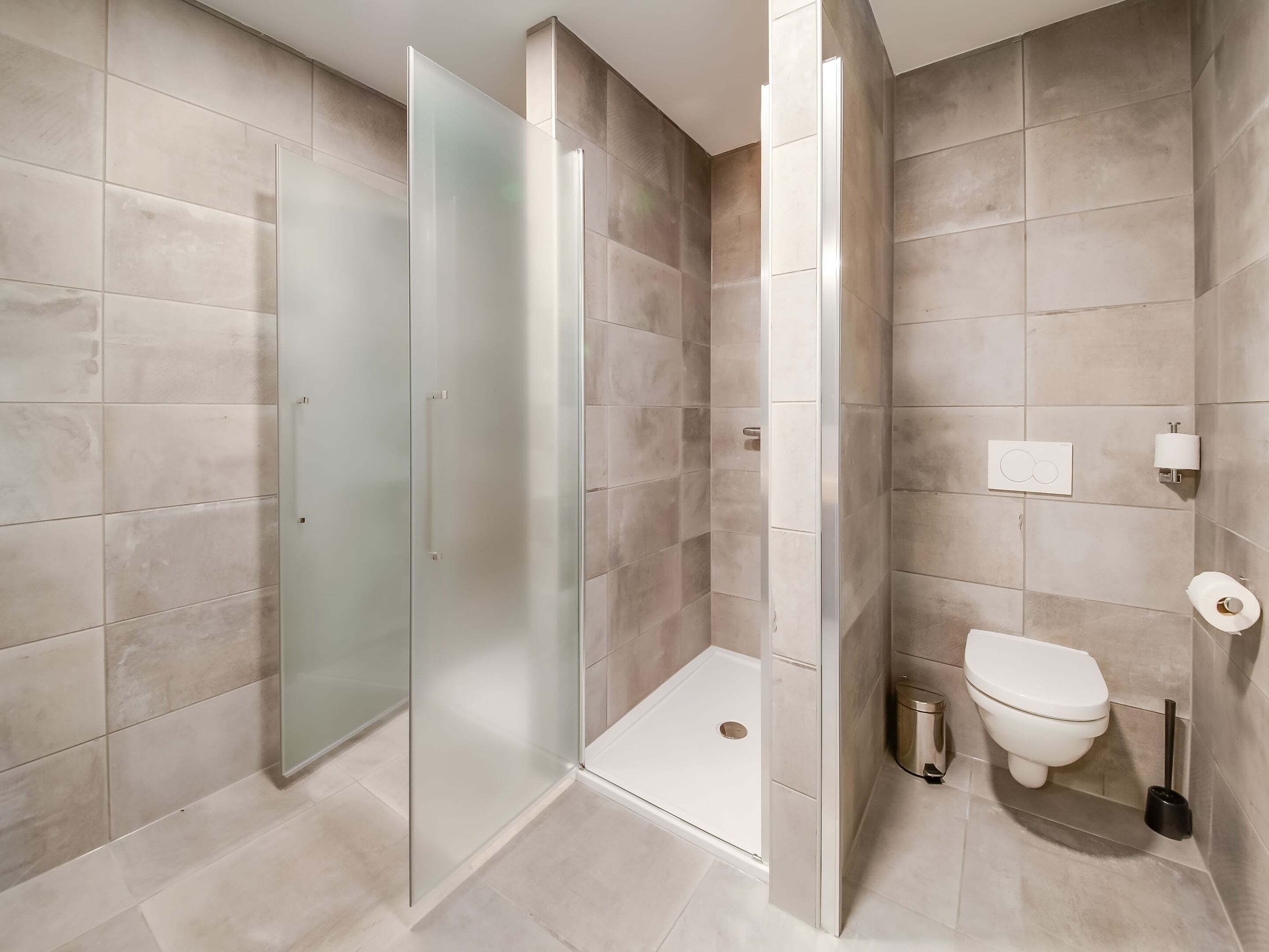 Ein modernes Badezimmer mit Glasdusche, Toilette und Bidet.