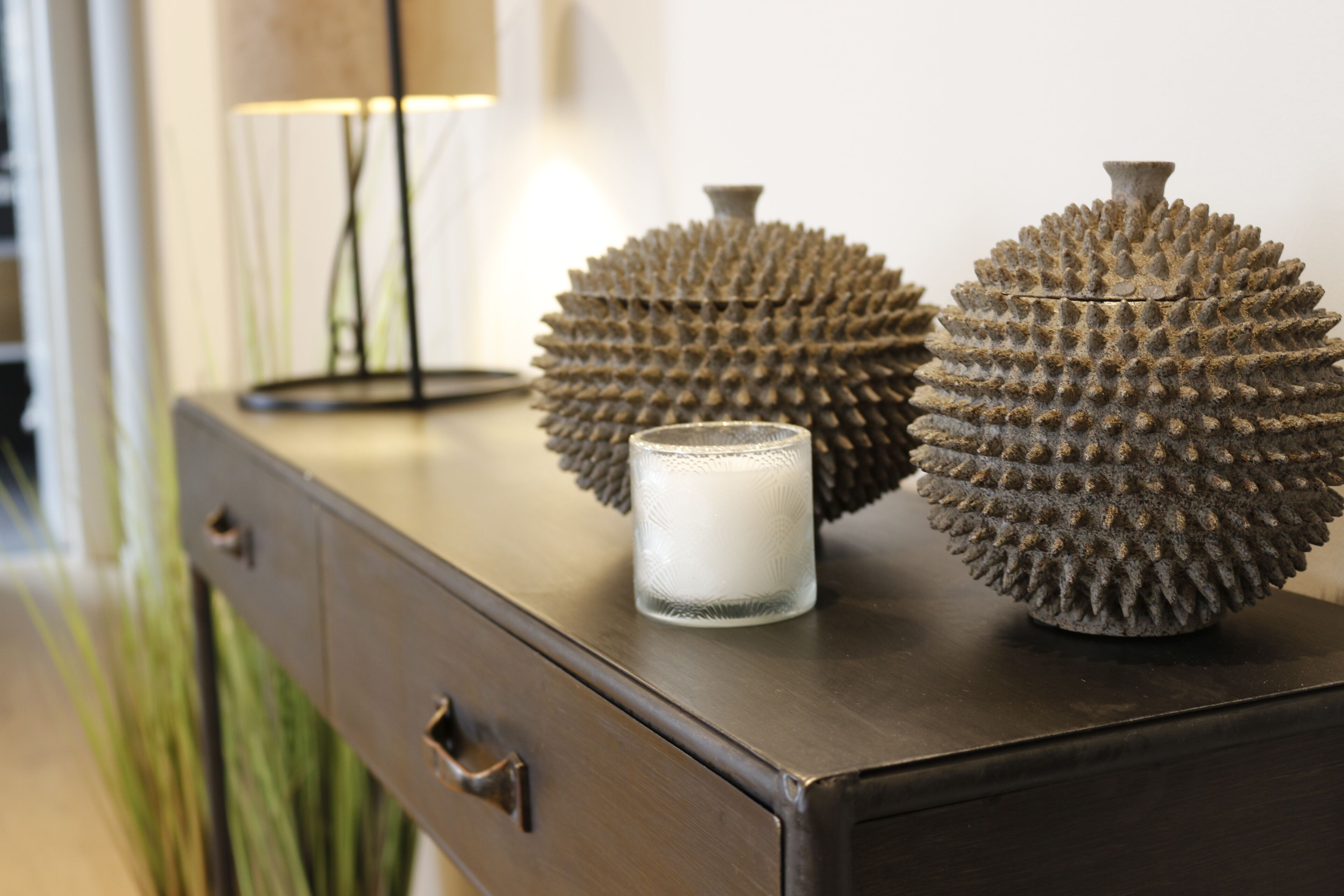 A dark wooden dresser with two textured spherical objects and a candle.