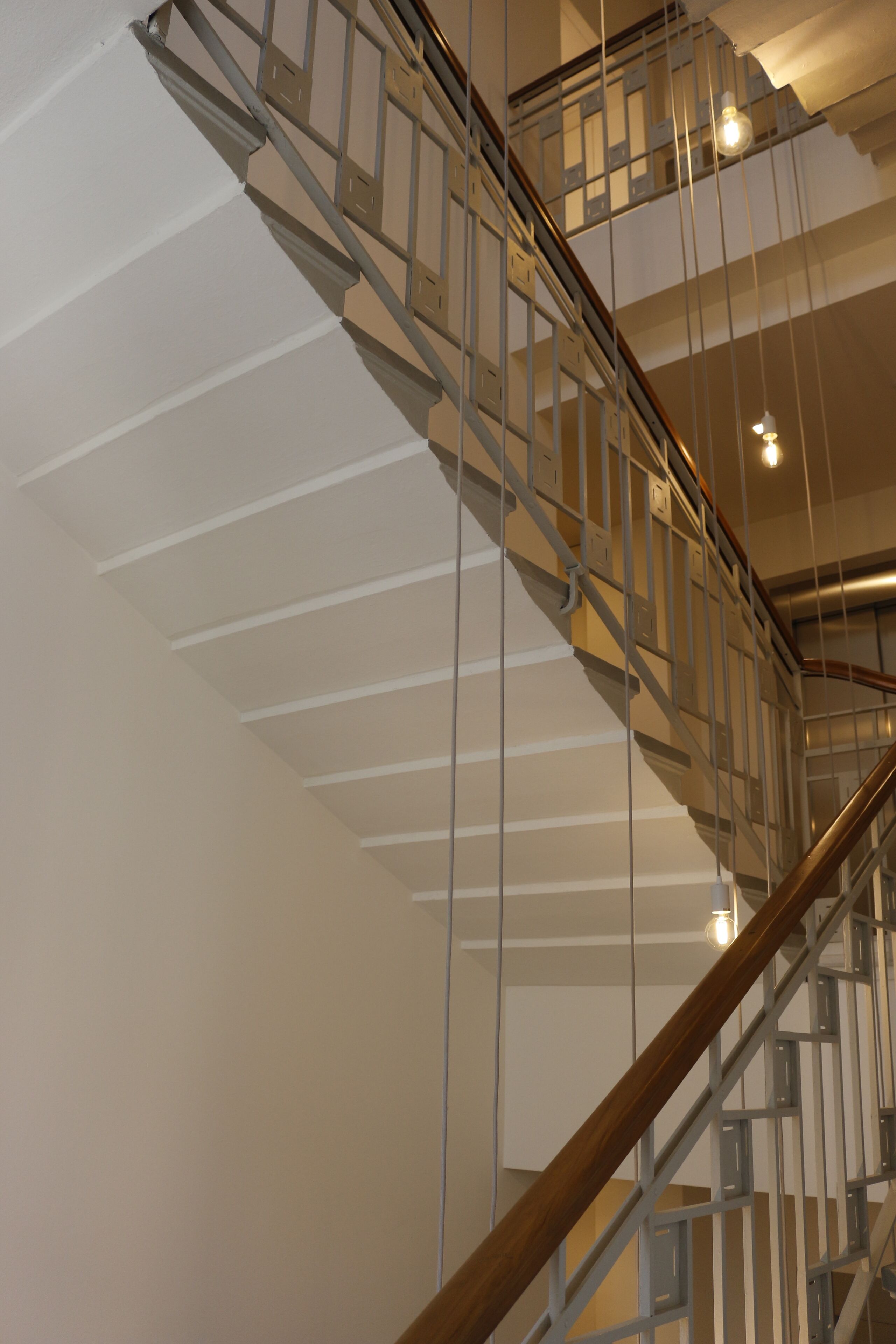 A modern staircase with glass railings and wooden handrails, leading to an upper level.