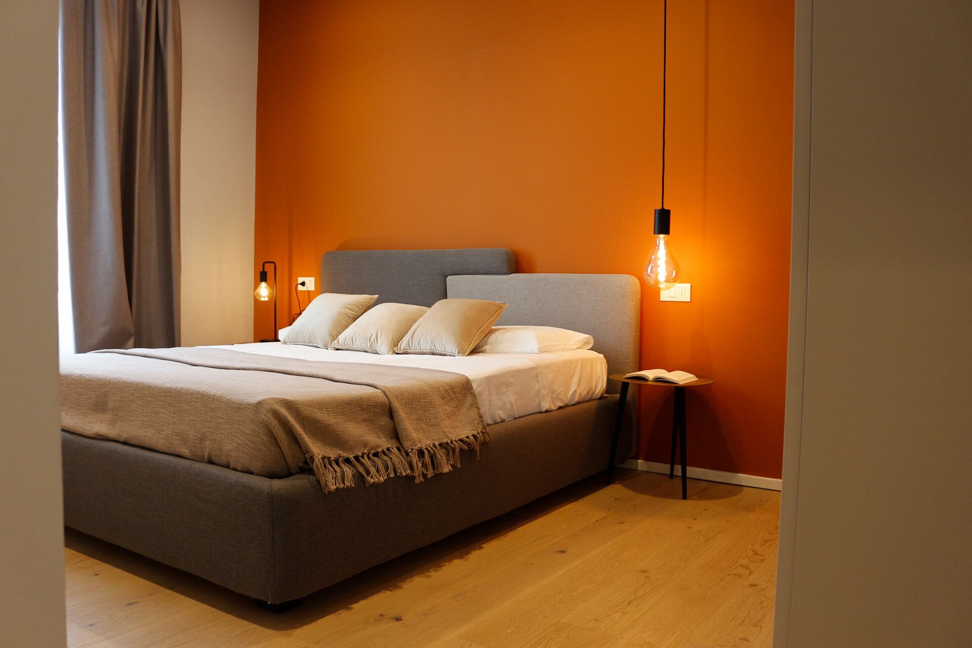 A modern bedroom with a large bed, two bedside tables, and a wall-mounted light fixture.