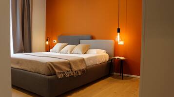 A modern bedroom with a large bed, two bedside tables, and a wall-mounted light fixture.