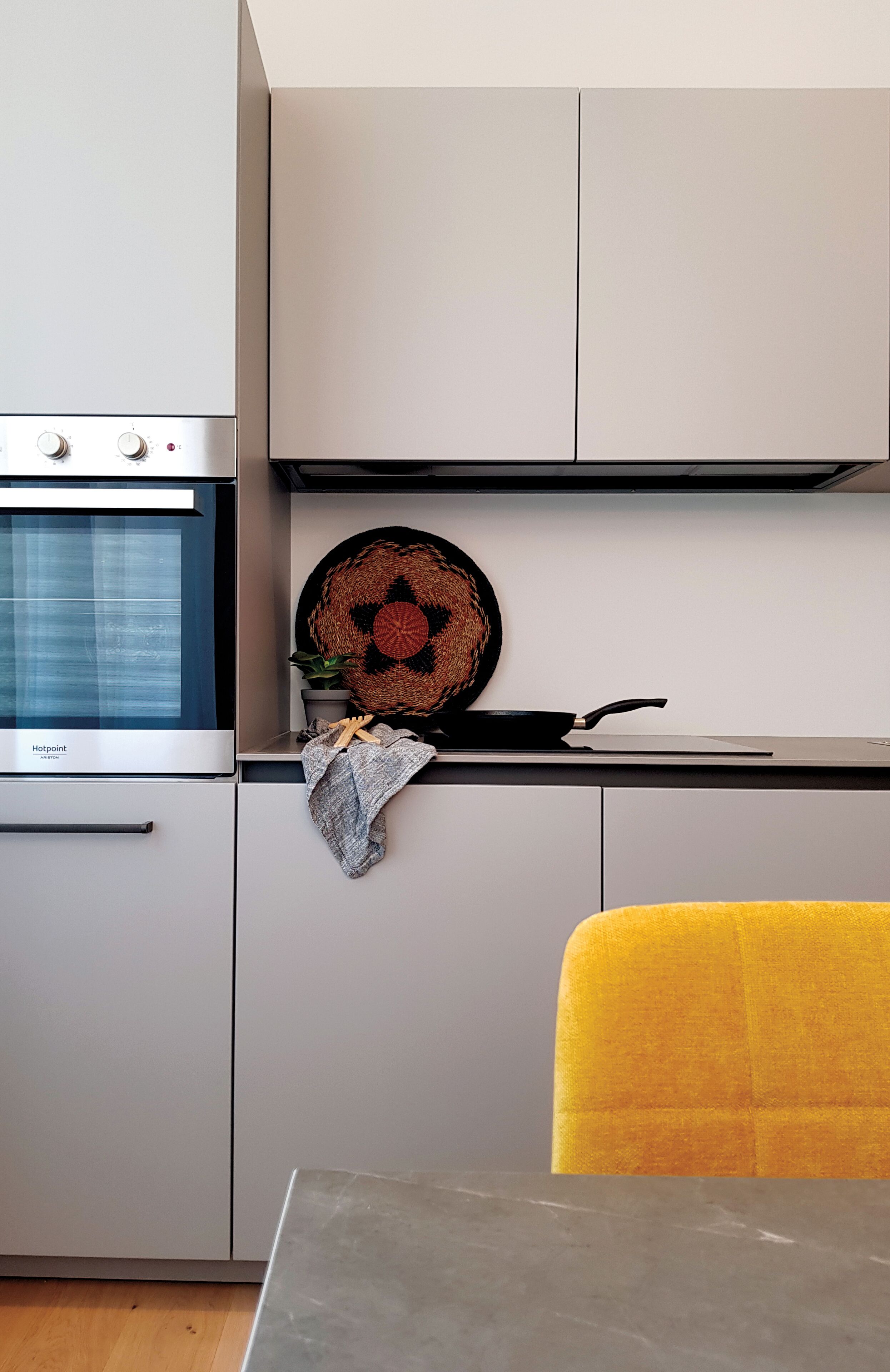 Una cocina con horno empotrado, una cesta colgante tejida y una sartén sobre la encimera.